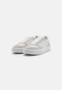 Baskets blanches avec une tige en daim et cuir, bout rond, lacets plats et semelle extérieure en caoutchouc blanc épaisse.