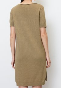Knit dress in olive green, short sleeves, round neckline, with side slits at the hem, showcasing a smooth texture and relaxed fit.