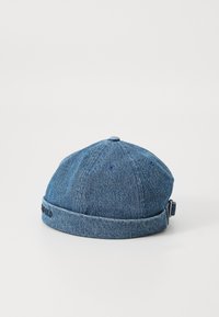 Denim cap in medium blue, featuring a round shape, stitched seams, and a branded cuff. Back strap adjusts for fit.