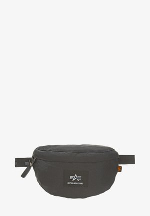 Sort stoftaljeveske med rund form, der har et logo patch, lynlås lukning og justerbar rem. Tekstureret overflade med syninger.