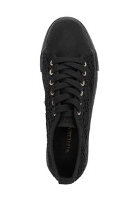 Zapatilla negra con un upper texturizado y una puntera de tela suave, con ojales dorados y cordones negros. Logo visible en la plantilla.