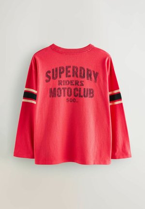 Röd långärmad t-shirt i bomull med ett stort svart tryck "SUPERDRY RIDERS MOTO CLUB 500cc" och svarta/röda ränder på ärmarna.