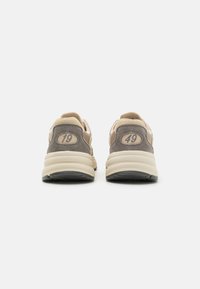 Graue und beige Sneakers mit einer strukturierten Wildleder-Oberfläche, gepolstertem Kragen, zweifarbiger Zwischensohle und den Rückennummern "19" und "49" an jeder Ferse.