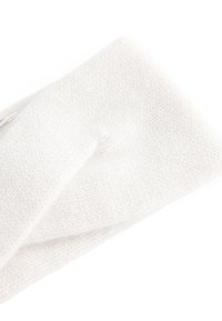 Bandeau tricoté blanc avec une texture douce, présentant un design torsadé au centre et une étiquette visible sur un bord.