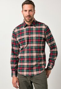 Rutig skjorta i grön, röd och krämfärgad; långa ärmar; två bröstfickor; rundad nederkant; bomullstyg med en mjuk textur.