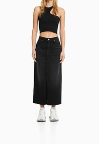 Černá džínová sukně s přímým střihem, délka ke kotníkům, přední rozparek a dvě kapsy. Doplněná o černý žebrovaný crop top a bílé tenisky.