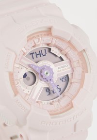 Zegarek Casio Baby-G z różowym silikonowym paskiem, okrągłą kopertą, wielofunkcyjnym cyferblatem, fioletowymi akcentami oraz wyświetlaczem cyfrowym pokazującym czas i dzień.