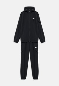 Μαύρη φόρμα που αποτελείται από μπουφάν με φερμουάρ και κουκούλα, καθώς και αντίστοιχο παντελόνι με τσέπες cargo. Κατασκευασμένη από λείο, ελαφρύ ύφασμα.