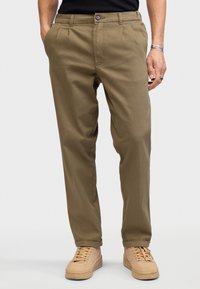 Khaki chinos gemaakt van een stevige stof, met een recht gesneden pijp, voorplooien en een rits met knoopsluiting.