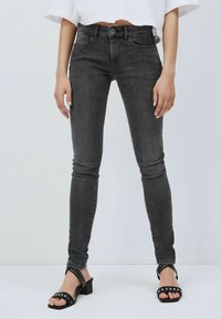 Svarta smala jeans i stretchdenim med midjehöjd. Har framfickor och en subtil tvätteffekt. Matchas med svarta klacksandaler med nitar.