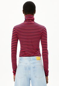 Rot-blau gestreiftes Rollkragenshirt mit langen Ärmeln, taillierter Passform und hohem Kragen, kombiniert mit hellen Denim-Jeans.