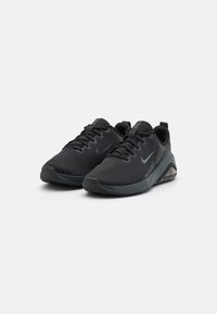 Scarpe da atletica nere con una tomaia in rete, dettagli testurizzati e suola ammortizzata. Caratterizzate da un logo tono su tono e un sistema di allacciatura.