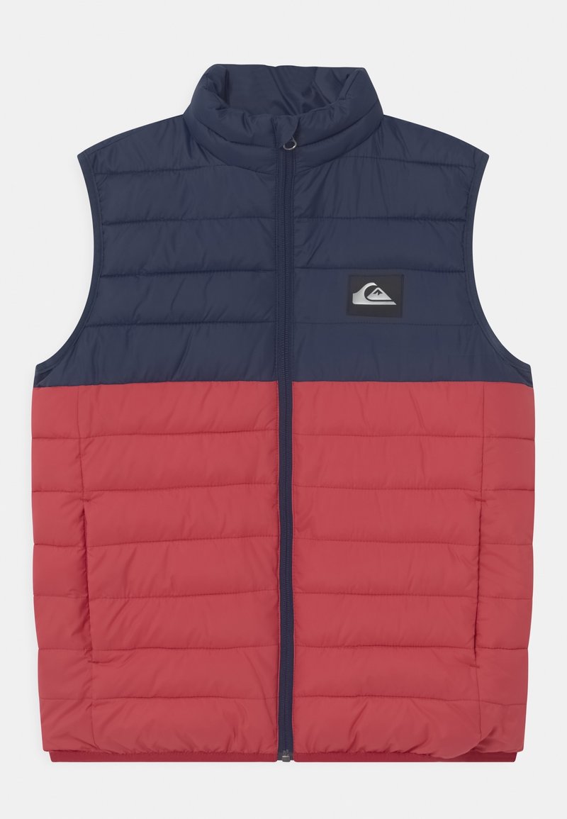 Veste matelassée sans manches avec partie supérieure bleu marine et partie inférieure rouge, fermeture éclair frontale, col montant et petit patch logo sur la poitrine.