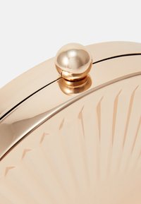 Metallic rose gold circular clutch with a textured sunburst pattern and a spherical clasp at the top, smooth finish, reflective surface.