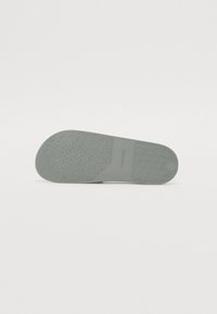 Talpă din cauciuc gri deschis, cu un model texturat pentru aderență, având un finisaj neted și un design cu vârf rotund.