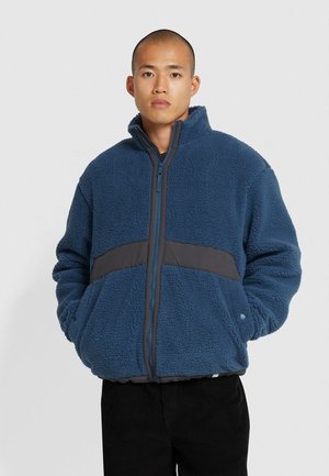 Fleecejacke in Dunkelblau mit grauen Einsätzen, hohem Kragen, Reißverschluss vorne und elastischen Bündchen. Weiche Textur, lässige Passform.
