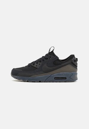 Sort og mørkegrå lavtop sports-sneakers med snørelukning foran, tekstureret sål og synlig luftstødabsorbering i mellemsålen.