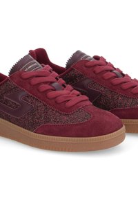 Burgundy sneakers with suede and glitter accents, featuring a rubber sole, round toe, and flat laces. Logo detail on tongue.
