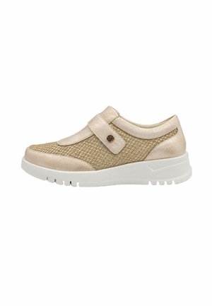 Zapatilla deportiva beige de mujer con tejido texturizado, una amplia correa con detalle de botón y una suela gruesa de goma blanca.