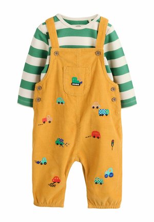 Gelbe Cord-Latzhosen mit buntem Auto- und LKW-Stick, kombiniert mit einem grün-weiß gestreiften Langarmshirt darunter.