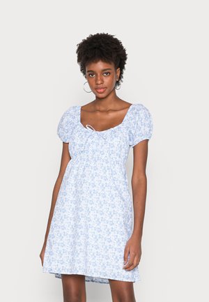 Vestido floral azul claro com mangas bufantes curtas, decote quadrado e um detalhe de laço na frente. Tecido fluido com um corte descontraído.