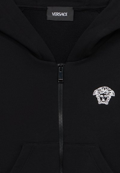 Μαύρο φούτερ με φερμουάρ κατασκευασμένο από απαλό ύφασμα με μπροστινή τσέπη. Διαθέτει λευκό κεντημένο λογότυπο Μέδουσας σ την αριστερή πλευρά του στήθους.