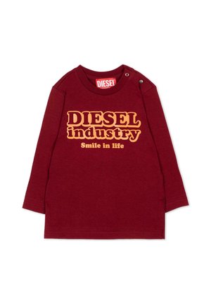 Bordowa koszulka z długim rękawem dla malucha z żółtym tekstem "DIESEL industry Smile in life" i zatrzaskami na ramieniu.