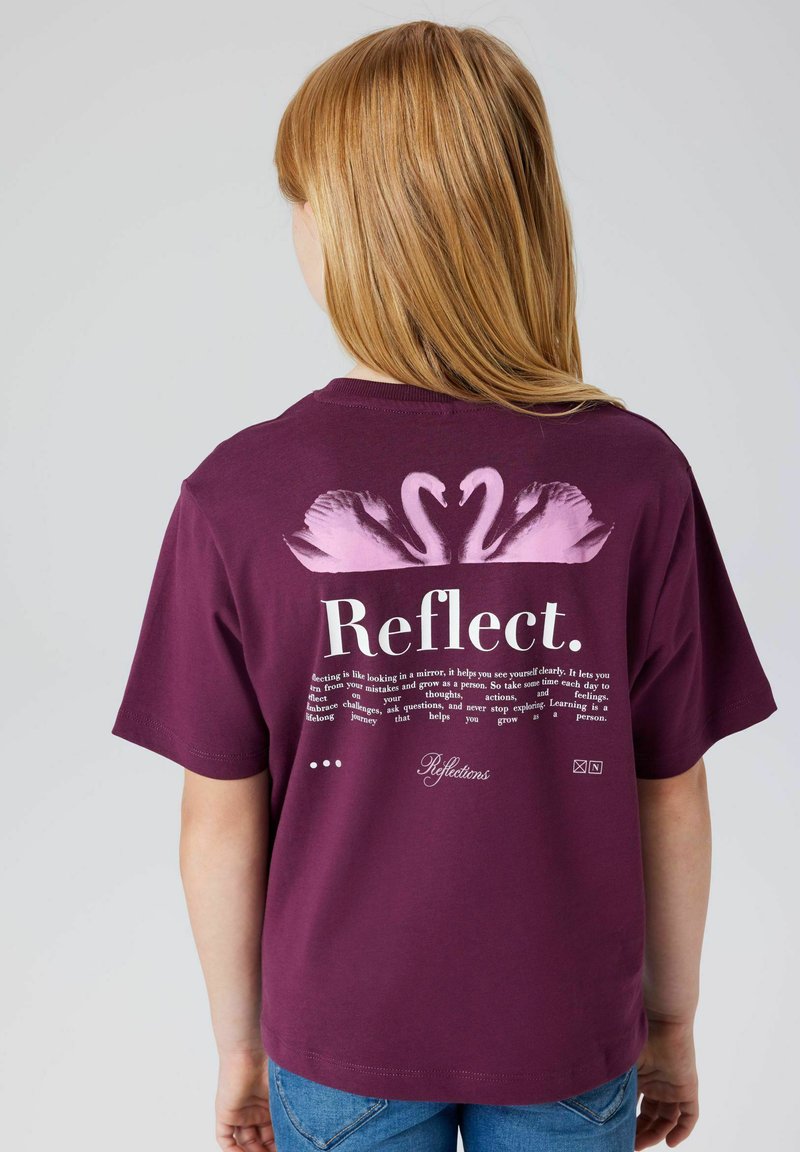 Bordowa koszulka z okrągłym dekoltem, krótkimi rękawami oraz różowym graficznym wzorem łabędzia z tyłu. Tekst podkreśla samorefleksję i naukę.