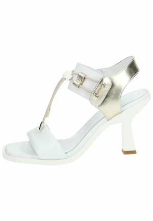 Hvid sandal med en metallisk guldaccent, med et T-strop design, elastisk bånd og en høj hæl med en blokbase. Glat tekstur.