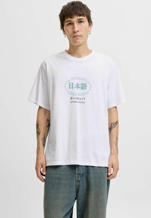 T-shirt en coton blanc à coupe décontractée, avec un texte graphique bleu en plusieurs langues centré sur la poitrine. Design décontracté et polyvalent.