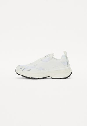 White athletic shoe with mesh and synthetic materials, chunky sole, round toe, black outsole, and subtle design details on the upper.