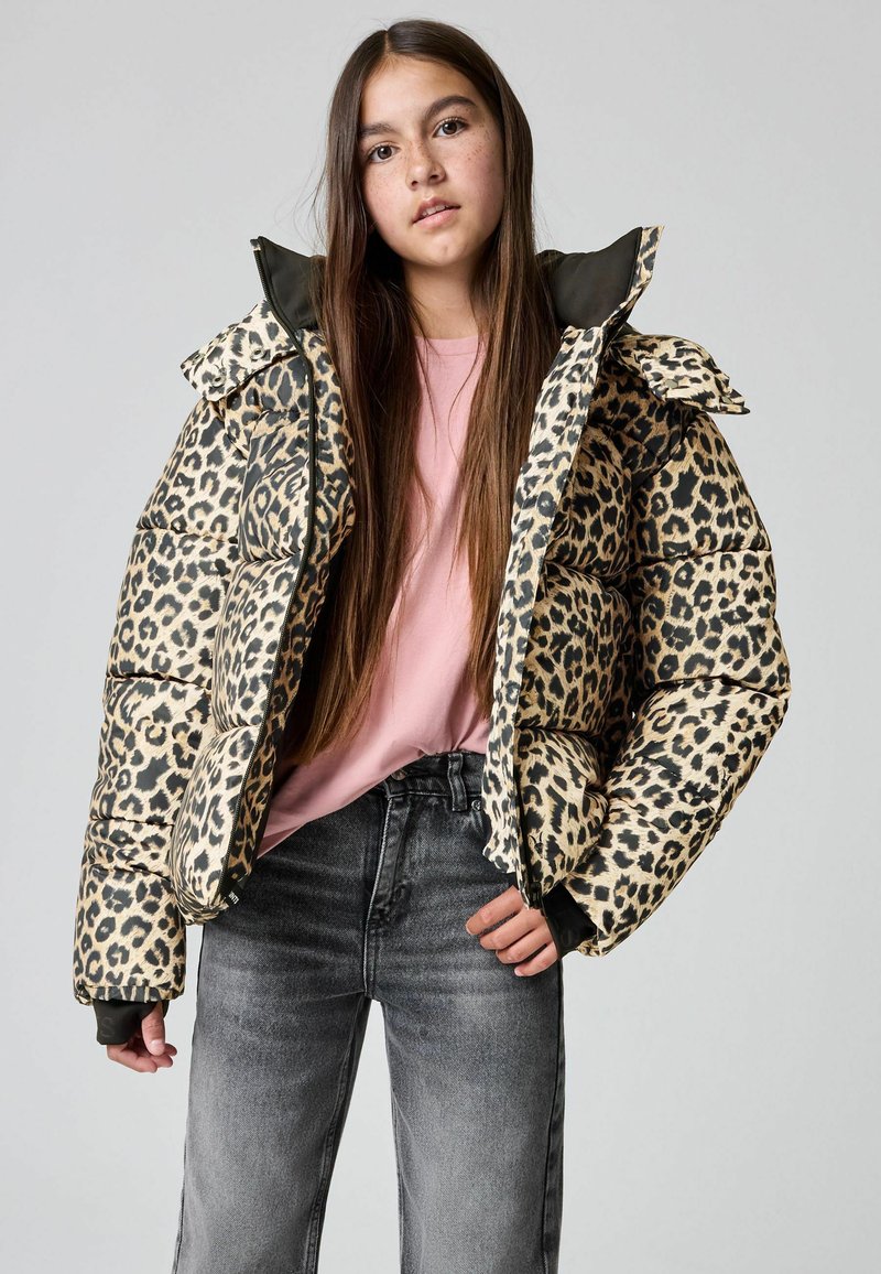 Polsteret jakke med leopardprint og høj krave, prydet med kontrasterende sorte detaljer, båret over en pink t-shirt og grå jeans.