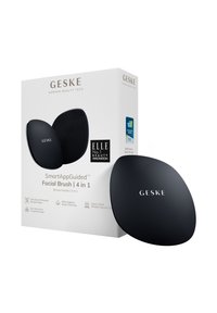 Black silicone facial brush with curved design, displayed next to sleek packaging. Features include soft tips and a targeted design for cleansing.