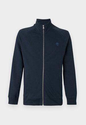 Jakna tamnoplave boje s patentnim zatvaračem po cijeloj dužini, visokim ovratnikom, dugim rukavima, bočnim džepovima i malim izvezenim logotipom stabla na lijevoj strani prsa.