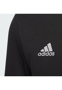 Black sweatshirt with a textured fabric and a silver embroidered Adidas logo on the left chest area. Simple, clean design.