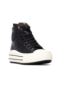 Zapatillas negras de caña alta hechas de cuero texturizado, con una suela de plataforma blanca con rayas negras y ojales naranjas.