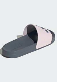 Sandały na płaskiej podeszwie z jasnoróżową syntetyczną cholewką i ciemnoszarym teksturowanym spodem. Posiadają szeroki pasek oraz logotyp na boku.