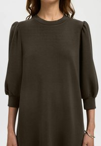 Tummanvihreä neulemekko, jossa on puff-hihat ja pyöreä pääntie. Sileä pinta joustavilla hihansuut. Yksinkertainen design ilman kuvioita.