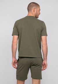 T-shirt en coton vert olive à manches courtes et col rond, associé à un short assorti avec des poches latérales et une coupe décontractée.