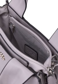 Borsa a tracolla grigia chiara con un esterno in sintentico liscio, hardware argentato, tasche con zip, manici piatti e una morbida fodera in tessuto. Comparti interni visibili.