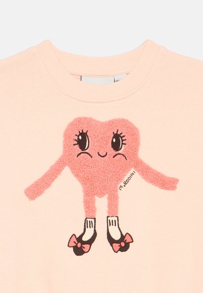 Felpa rosa con una grafica a cuore testurizzata con braccia, scarpe nere e fiocchi. Materiale in cotone con scollatura rotonda.