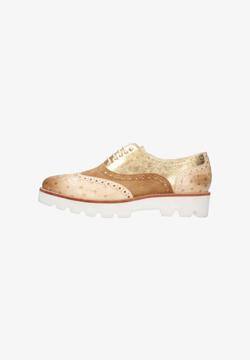 Chaussure brogue en tons de beige et doré avec un design perforé, réalisée en cuir suédé et métallisé, et dotée d'une semelle épaisse blanche. Présente des lacets pour la fermeture.