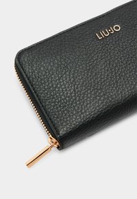 Portafoglio in pelle nera testurizzata con dettagli in zip dorati e logo "LIU•JO" in rilievo. Presenta una superficie liscia e forma rettangolare.