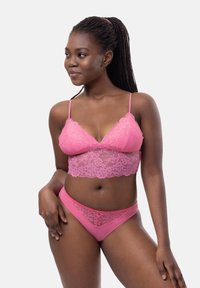 Roze kanten bralette met verstelbare bandjes en bloemenpatroon, gecombineerd met bijpassende roze kanten slipjes. Gladde textuur.
