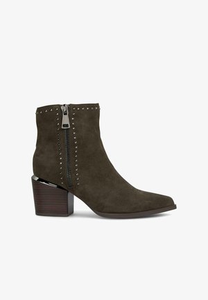 Zielone zamszowe botki za kostkę z ostro zakończonym noskiem, bocznym zamkiem błyskawicznym i metalowymi ćwiekami wzdłuż zamka. Posiadają masywny brązowy obcas.