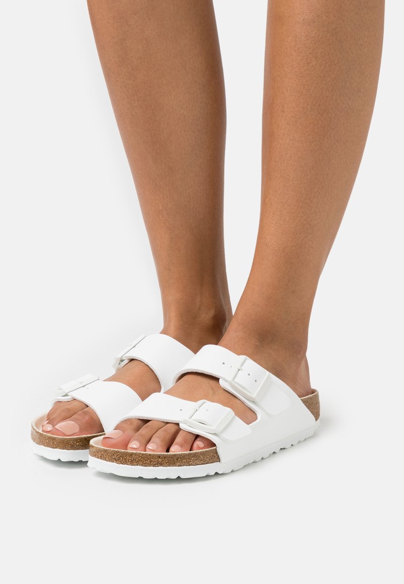 Witte sandalen met twee verstelbare riemen, kurken voetbed en witte rubberen zool. Heeft een gladde textuur en een afgeronde te ontwerpen.