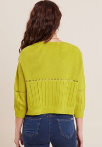 Maglione di colore verde lime in maglia con vestibilità ampia, caratterizzato da un motivo testurizzato e maniche a tre quarti. Decorato con dettagli ad aereazione lungo la schiena.
