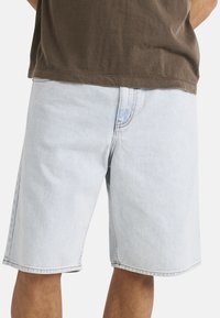 Bermudas de mezclilla azul claro con un ajuste holgado, que cuentan con un corte recto, costuras visibles y bolsillos laterales.