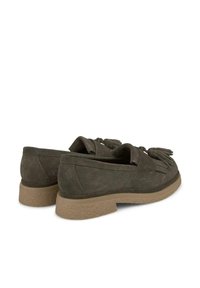 Mocassini in suede oliva con accenti frangi e punta arrotondata, e suola in gomma texturizzata. Dettaglio di cucitura sottile lungo i bordi.
