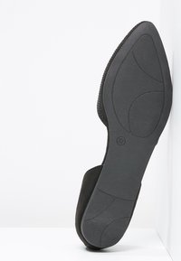 Zapato de ante negro con una parte superior texturizada y suela de goma lisa. Presenta una forma contorneada y tiene la talla 37 marcada en la parte inferior.